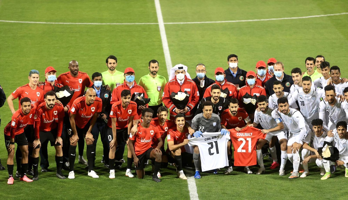 Al Rayyan and Al Wakrah players and officials pose for a photograph displaying jerseys with Ousmane Coulibaly's name on them.   