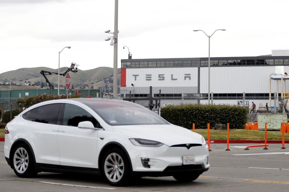 A Tesla vehicle drives past Tesla's primary vehicle factory after CEO Elon Musk announced he was defying local officials' coronavirus disease (COVID-19) restrictions by reopening the plant in Fremont, California, U.S. May 11, 2020. REUTERS/Stephen Lam

