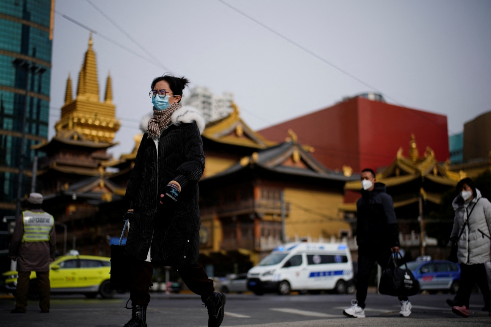 People wearing protective masks walk on a street, following new cases of the coronavirus disease (COVID-19), in Shanghai, China January 17, 2022. REUTERS/Aly Song