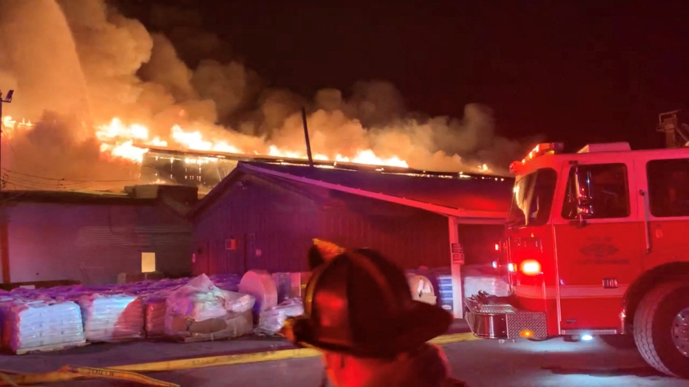 A firefighter walks past a fire engine as Weaver Fertilizer Plant burns on Cherry Street in Winston-Salem, North Carolina, U.S., January 31, 2022, in this screen grab taken from a video recorded on January 31, 2022. City of Winston-Salem via Facebook/Handout via Reuters 