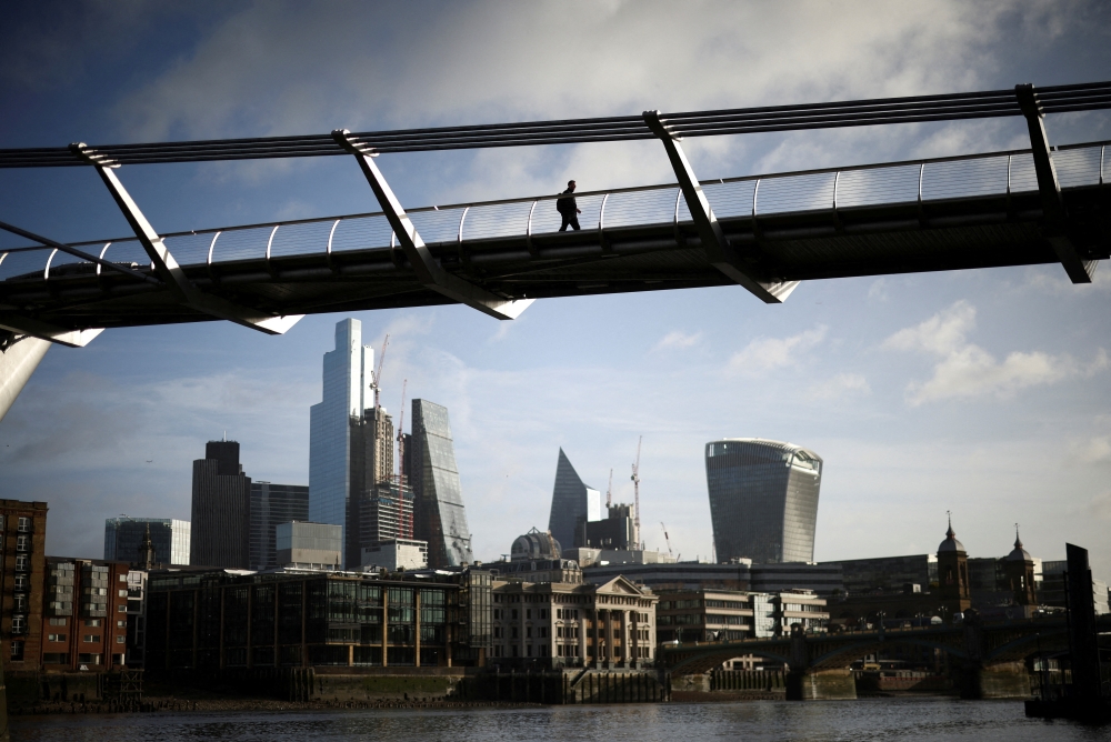 FILE PHOTO: The City of London financial district is seen as people walk over Millennium Bridge in London, Britain, February 16, 2022. REUTERS/Henry Nicholls