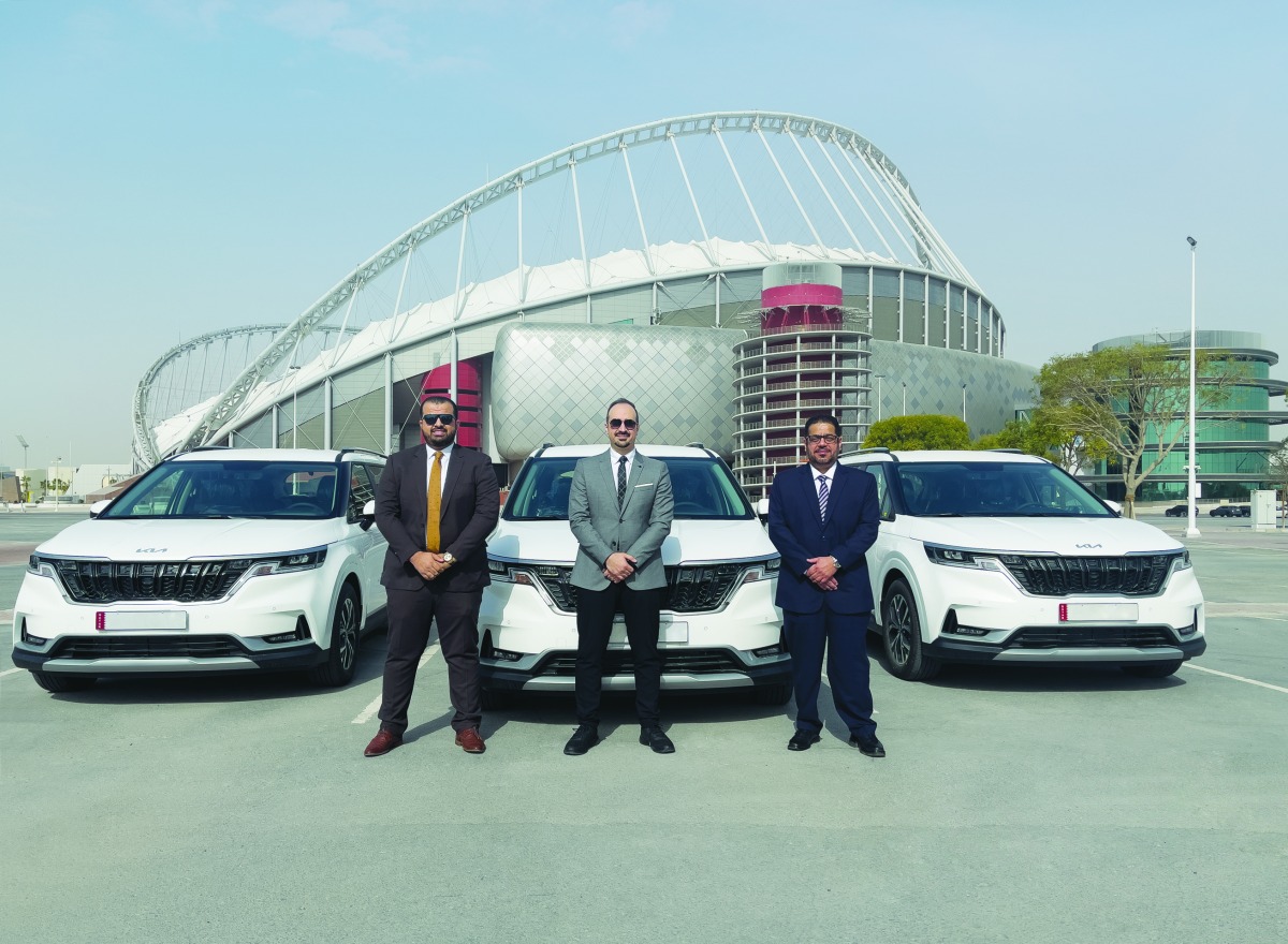 Officials from Kia Qatar and Aayan Leasing pose for a photo with Carnival vehicles at the background, in Doha, recently. 