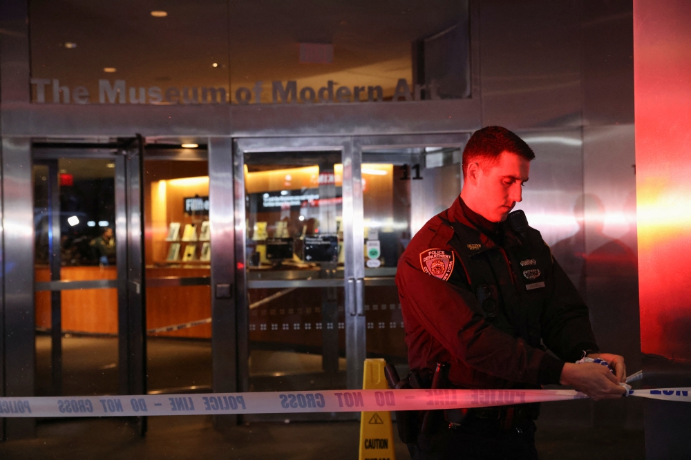 A member of the New York City Police Department (NYPD) ties police tape at the entrance of the Museum of Modern Art (MOMA) after an alleged multiple stabbing incident, in New York, U.S., March 12, 2022. REUTERS/Andrew Kelly