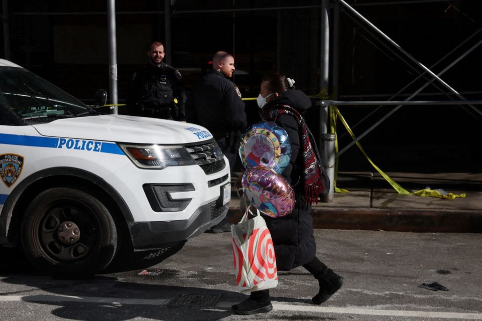 A woman walks with balloons by an area where NYPD police have marked off an area where a 43-year-old man was found dead on Sunday evening in New York City, U.S., March 14, 2022. REUTERS/Shannon Stapleton

