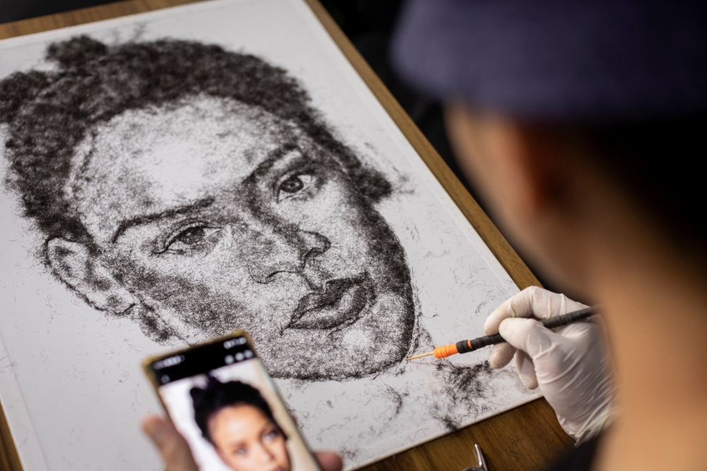 Artist and Filipino seafarer Jesstoni Garcia works on a portrait of Rihanna, made out of human hair, in San Juan City, Philippines, March 10, 2022. Picture taken March 10, 2022. REUTERS/Eloisa Lopez