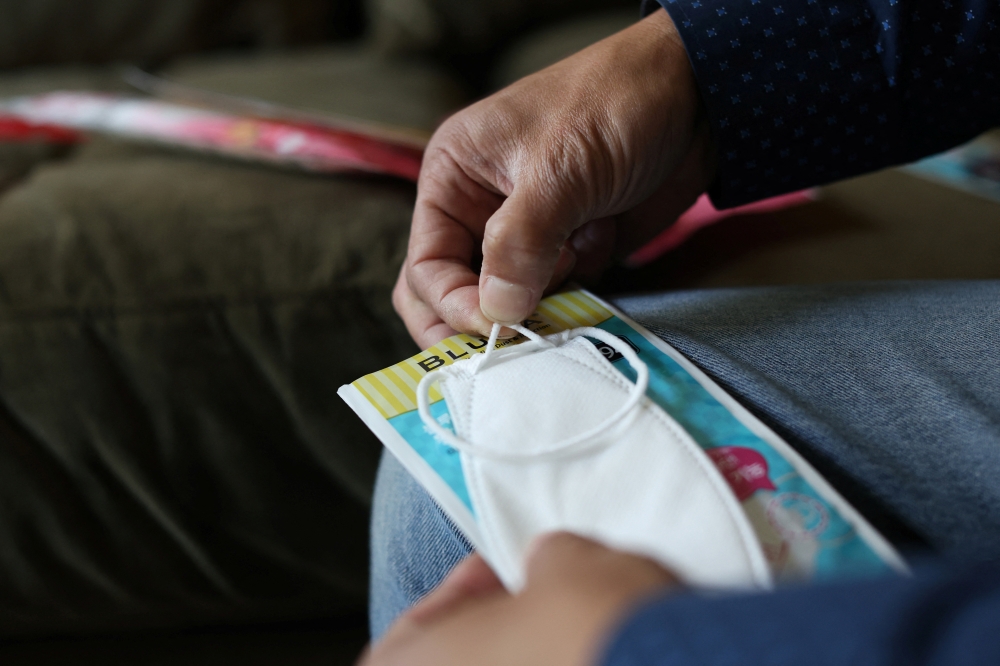 LA-based freight forwarder Tony Chen holds the adjustable ear strap of a kid-sized KF94 mask made in South Korea, in his living room in South Pasadena, California, U.S., January 27, 2022. Picture taken January 27, 2022. REUTERS/Mario Anzuoni