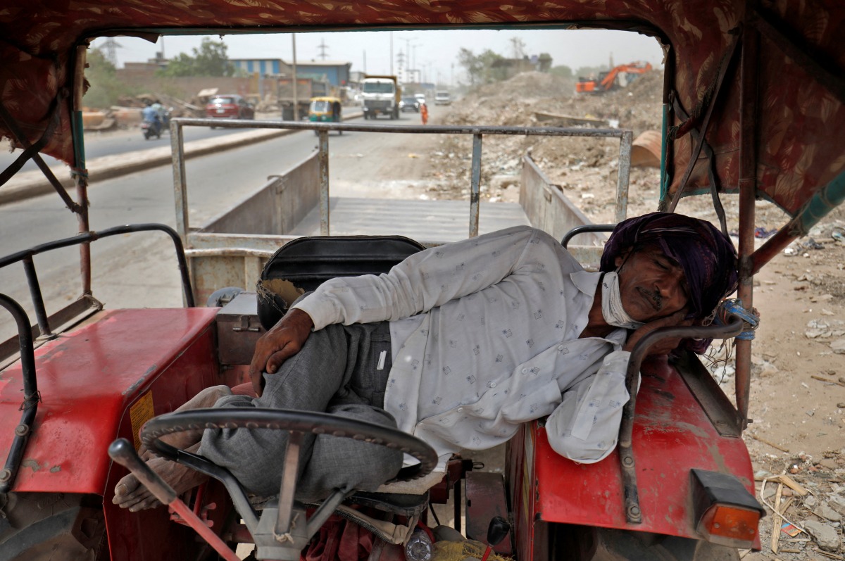 A man sleeps in his tractor parked alongside a road on a hot-weather day on the outskirts of Ahmedabad, India, May 23, 2022. REUTERS/Amit Dave
