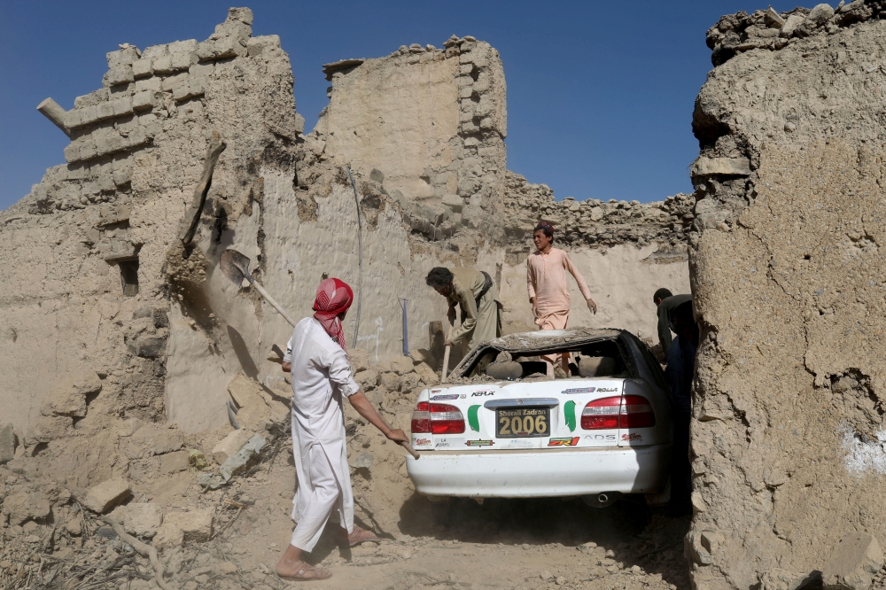 Afghan people try to retrieve a car from the debris of damaged houses after the recent earthquake in Wor Kali village in the Barmal district of Paktika province, Afghanistan, June 25, 2022. (REUTERS/Ali Khara)