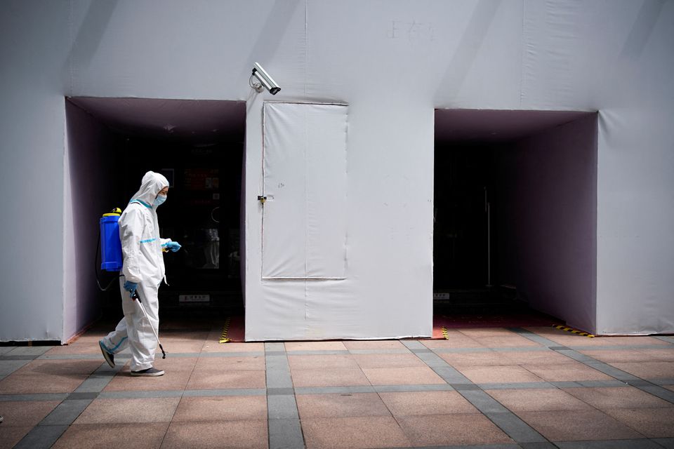 A worker in a protective suit disinfects following the coronavirus disease (COVID-19) outbreak, under a surveillance camera on street in Shanghai, China July 1, 2022. REUTERS/Aly Song


