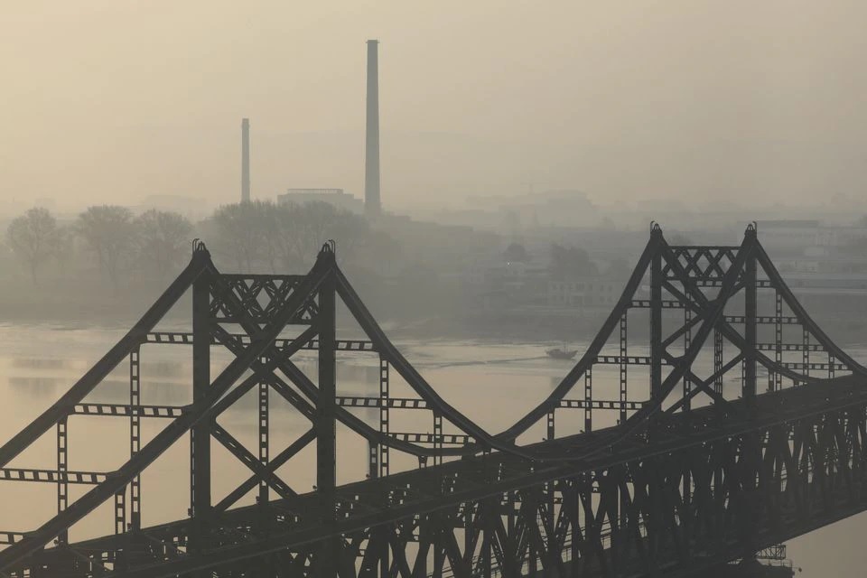 Buildings in North Korea's Sinuiju are seen behind the Friendship Bridge over the Yalu river, during sunrise in Dandong, Liaoning province, China April 20, 2021. REUTERS/Tingshu Wang

