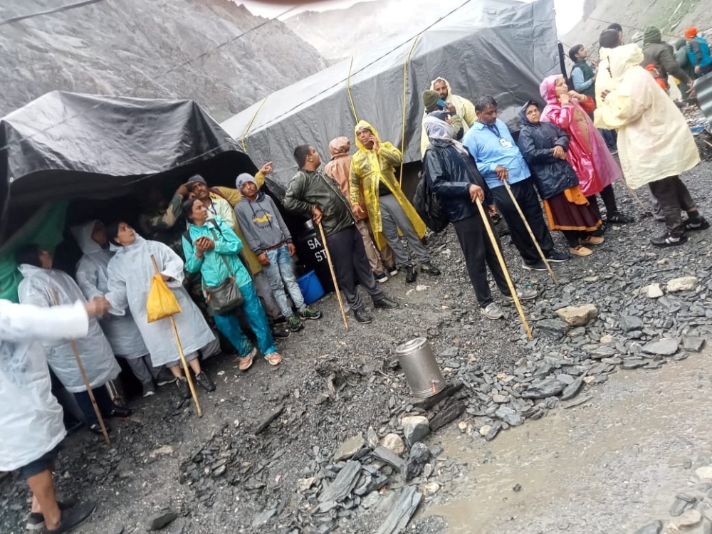 People stand outside tents after a cloudburst near the holy Amarnath cave shrine in Kashmir, July 8, 2022. (Reuters)