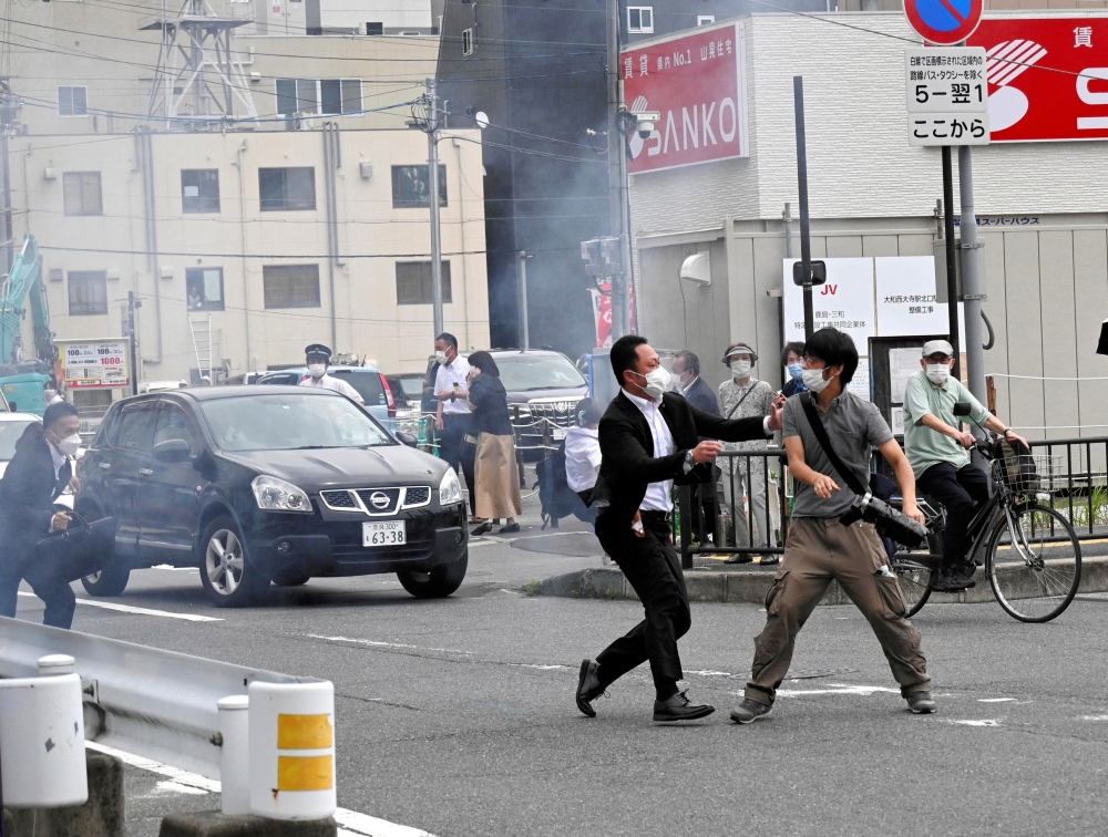 A police officer detains a man, believed to have shot former Japanese Prime Minister Shinzo Abe, in Nara, western Japan July 8, 2022. (The Asahi Shimbun/via Reuters)
