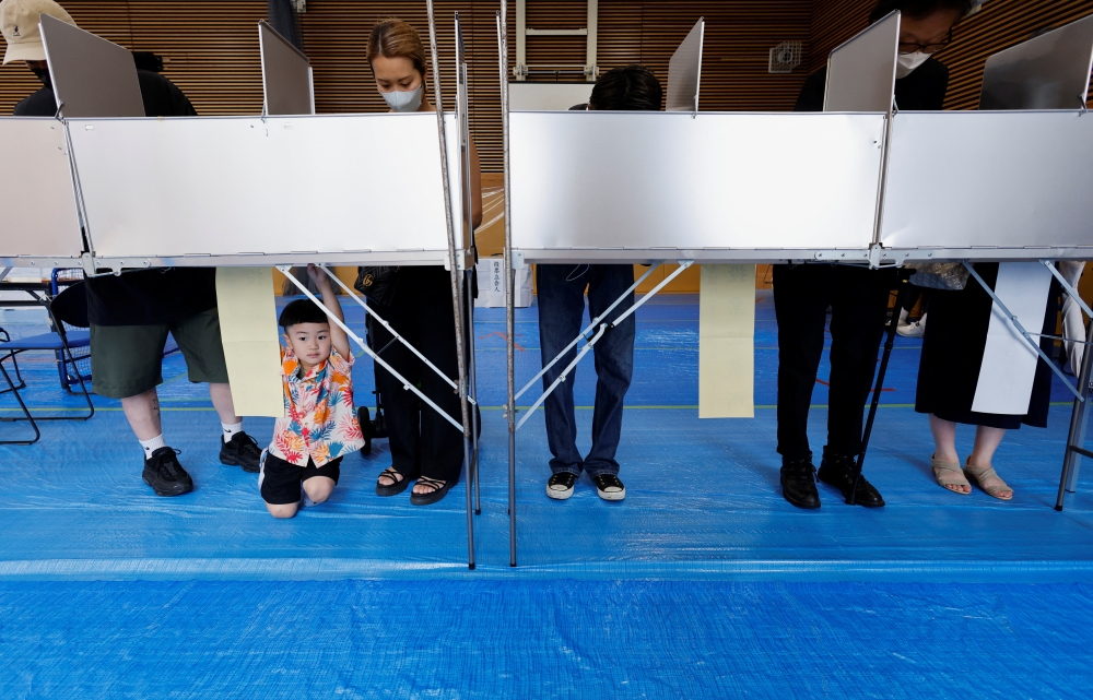 Voters prepare to cast their ballots in the upper house election at a polling station in Tokyo, Japan July 10, 2022. REUTERS/Issei Kato
