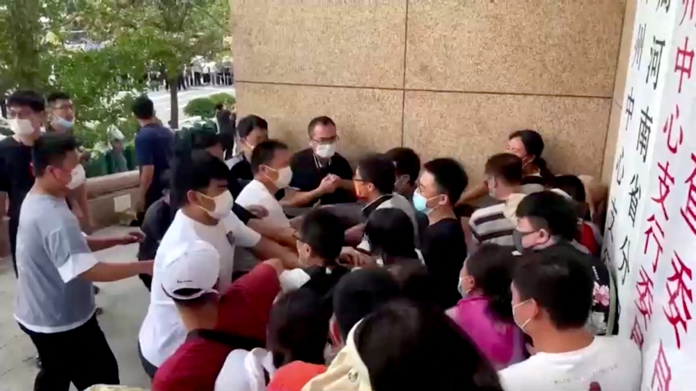 Plain-clothed security personnel scuffle with demonstrators during a protest over the freezing of deposits by some rural-based banks, outside a People's Bank of China building in Zhengzhou, Henan province, China July 10, 2022, in this screengrab from video obtained by REUTERS