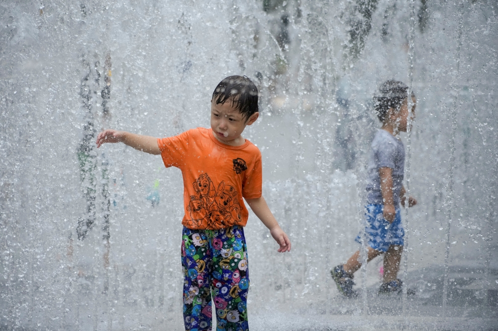 A child cools off in a fountain on a hot day, following a coronavirus disease (COVID-19) outbreak, in Shanghai, China July 12, 2022. REUTERS/Aly Song