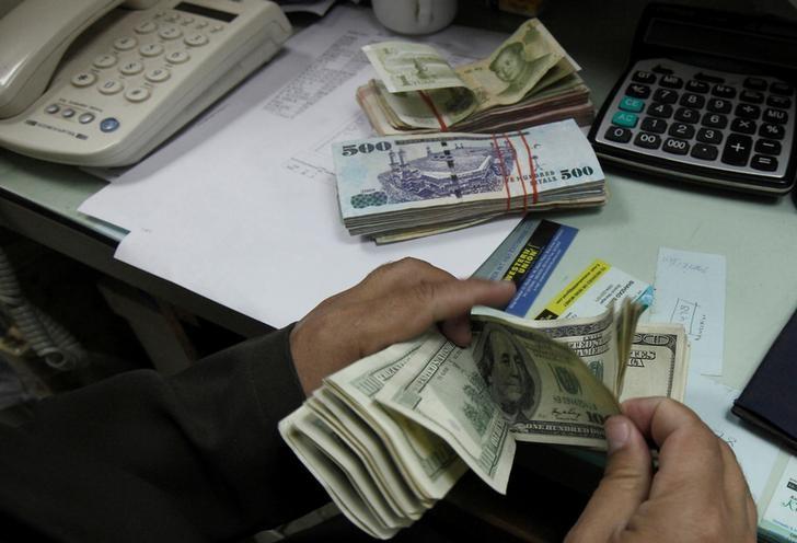 A currency exchange trader counts money at his office in Islamabad November 26, 2012. REUTERS/Faisal Mahmood/Files