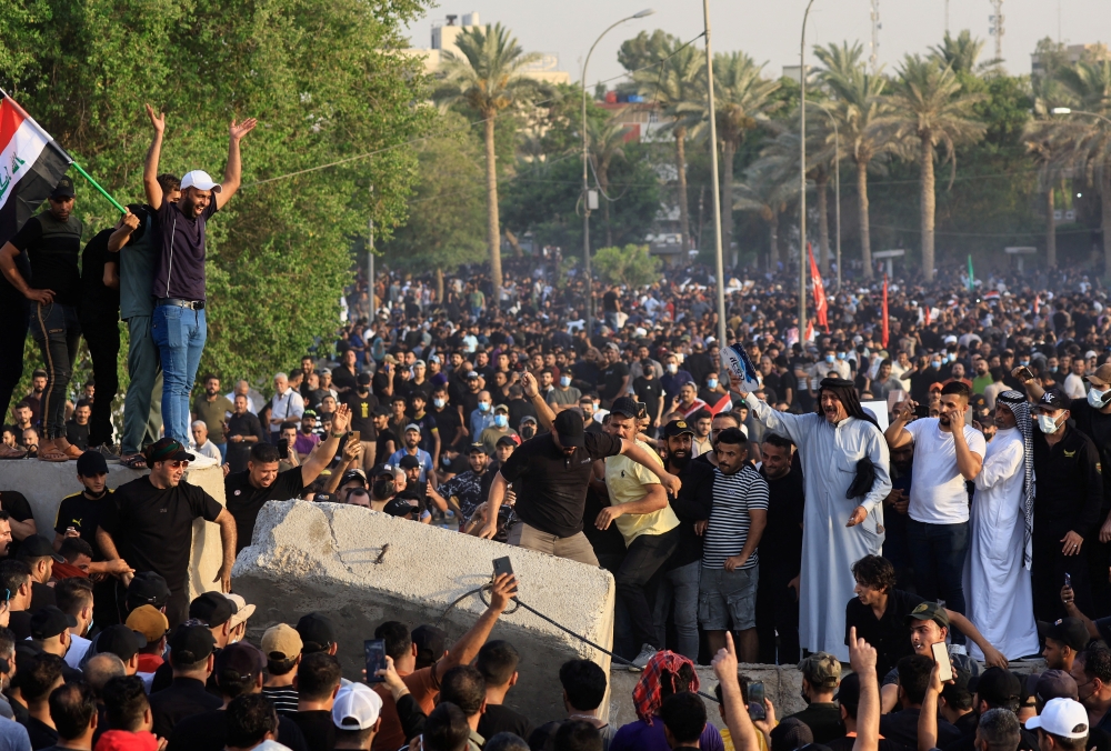 Shi'ite parties try to push down a piece of a concrete wall during a protest, amid a political crisis, near Green Zone, in Baghdad, Iraq, August 1, 2022. (REUTERS/Thaier Al-Sudani)