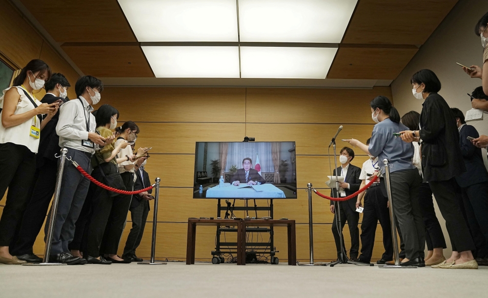 Japan's Prime Minister Fumio Kishida is seen on a screen as he answers remotely a question from reporters, after he tested positive for the coronavirus disease the previous day, at his residence in Tokyo, Japan, in this photo taken by Kyodo on August 22, 2022. (Reuters)