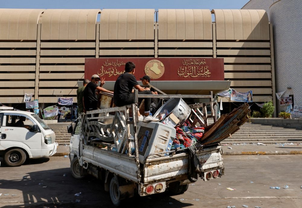Followers of Iraqi cleric Moqtada al-Sadr carry their belongings on a pick up vehicle as they withdraw from the streets after violent clashes, outside the parliament at the Green Zone in Baghdad, Iraq, on August 30, 2022. REUTERS/Ahmed Saad