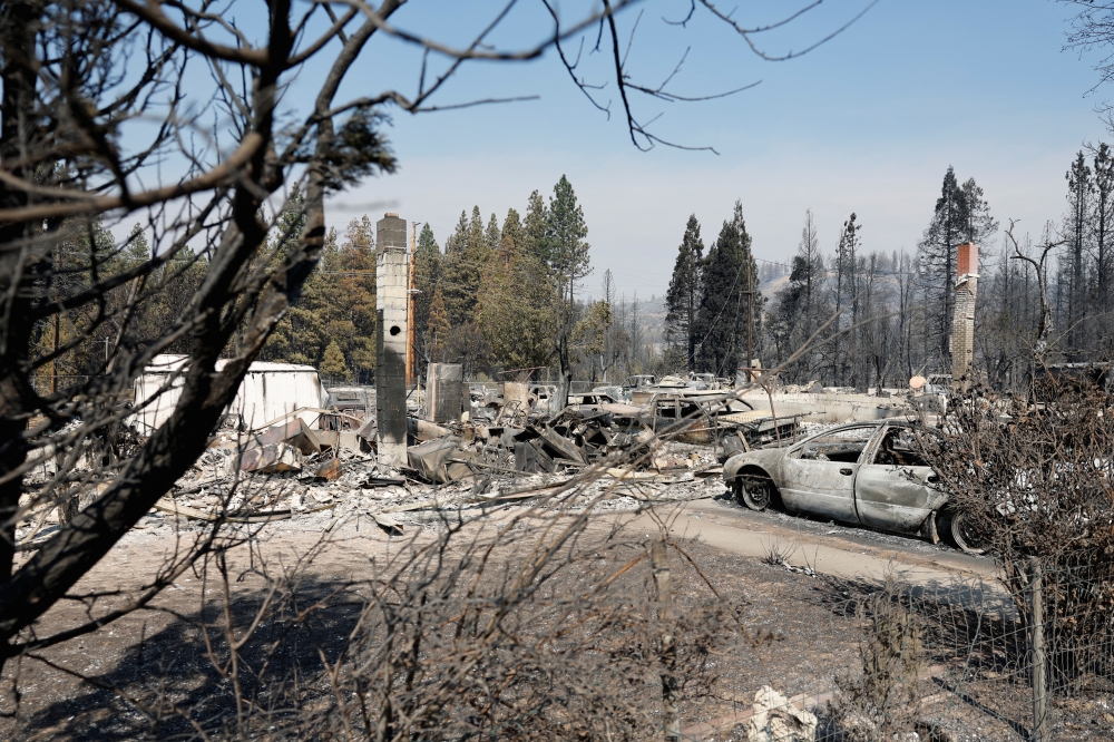 A burned car stands near a burned down home in the aftermath of the Mill Fire, in Weed, California, on September 3, 2022. REUTERS/Fred Greaves