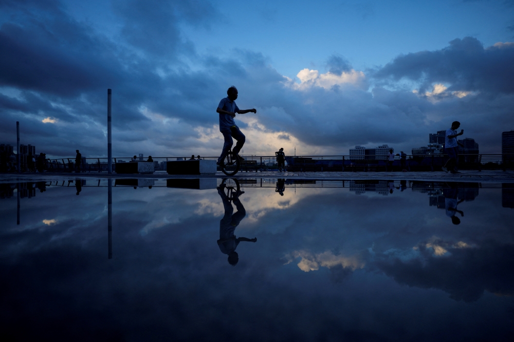 A man rides a unicycle on a bank of Huangpu River as Typhoon Hinnamnor approaches, following the coronavirus disease (COVID-19) outbreak, in Shanghai, China, September 3, 2022. REUTERS/Aly Song
