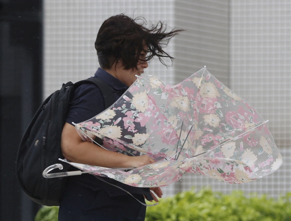 A woman makes her way in strong winds brought by Typhoon Hinnamnor in Naha, Okinawa prefecture, Japan, in this photo taken by Kyodo on September 4, 2022. Kyodo/via Reuters