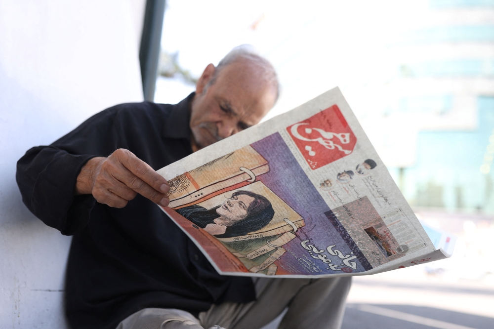 A man views a newspaper with a cover picture of Mahsa Amini, a woman who died after being arrested by the 