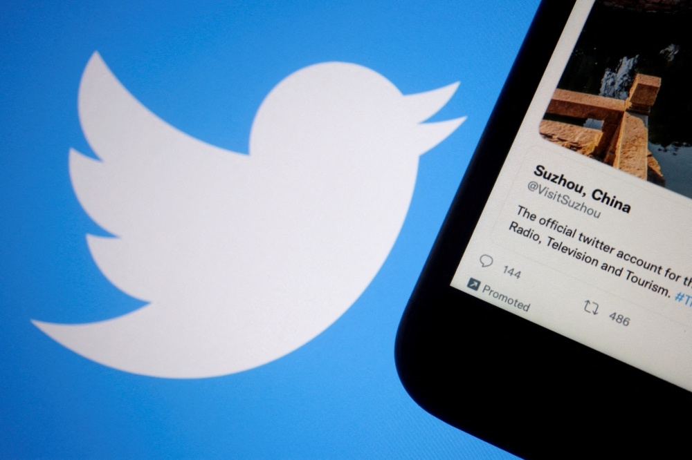A promoted tweet on China's Suzhou city is displayed on a mobile phone near a Twitter logo, in this illustration picture taken on September 8, 2022. REUTERS/Florence Lo