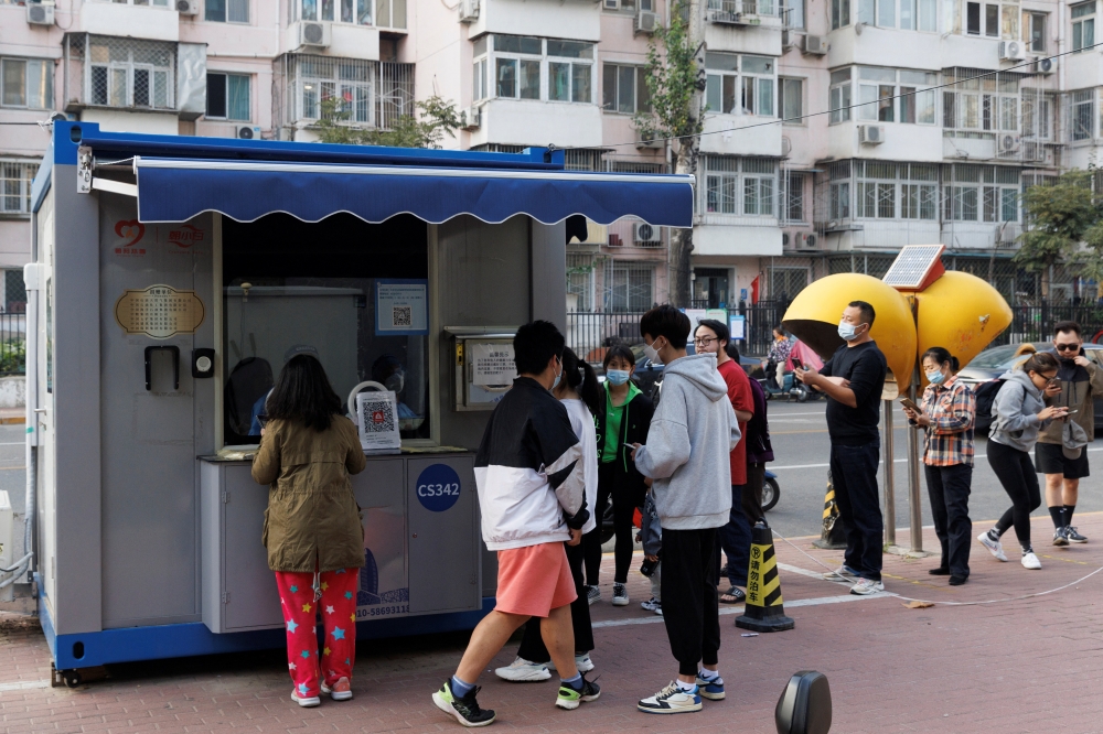 People line up to get a swab at a nucleic acid testing station set up to trace possible coronavirus disease (COVID-19) outbreaks in Beijing, China, October 7, 2022. REUTERS/Thomas Peter