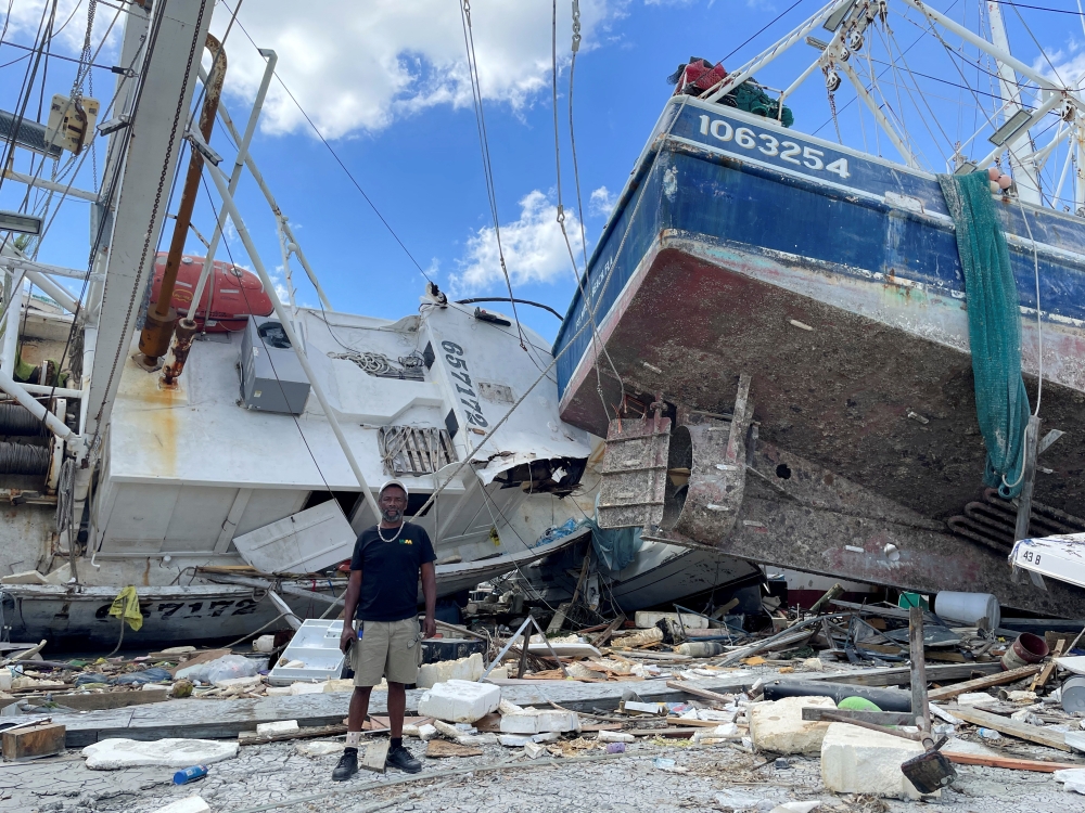 Ricky Moran stands in front of a shrimp boat, captained by him, and two other damaged boats, which were hit by Hurricane Ian at a Fort Myers Beach dock, Florida, U.S., October 5, 2022. REUTERS/Rod Nickel