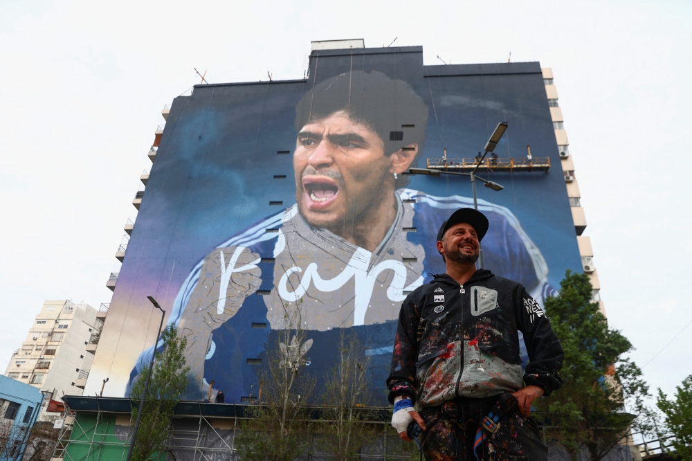 Artist Martin Ron poses for a picture in front of his mural depicting late soccer legend Diego Armando Maradona, which will be presented on the anniversary of Maradona, the 30th of October, in Buenos Aires, Argentina on October 19, 2022. REUTERS/Tomas Cuesta