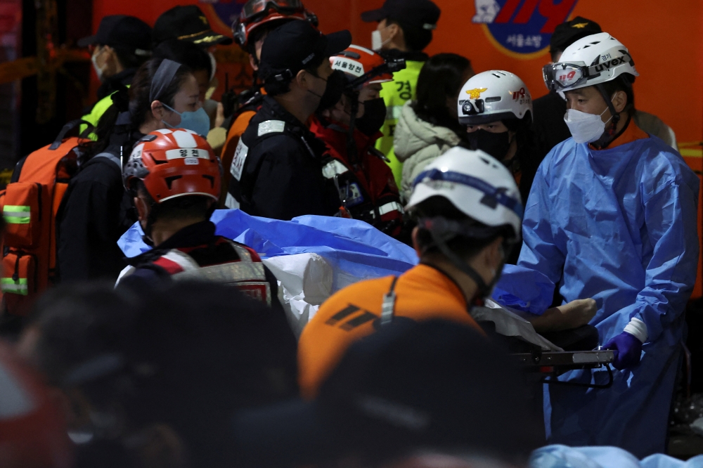 Rescue team members move a body at the scene where dozens of people were injured in a stampede during a Halloween festival in Seoul, South Korea, on October 29, 2022. REUTERS/Kim Hong-ji