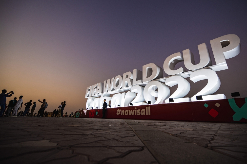 People take photos of the FIFA World Cup Qatar 2022 sign on the Doha Corniche on November 14, 2022. (AFP/Andrej Isakovic)