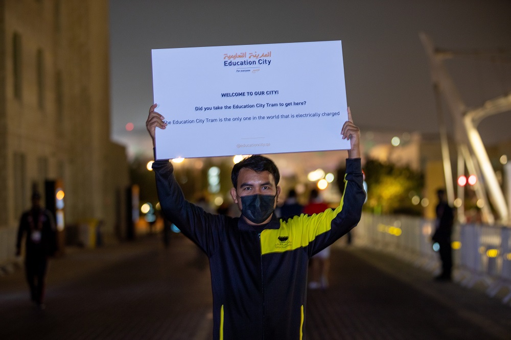 An educational volunteer holding up a sign outside Education City stadium during the FIFA Arab World Cup.