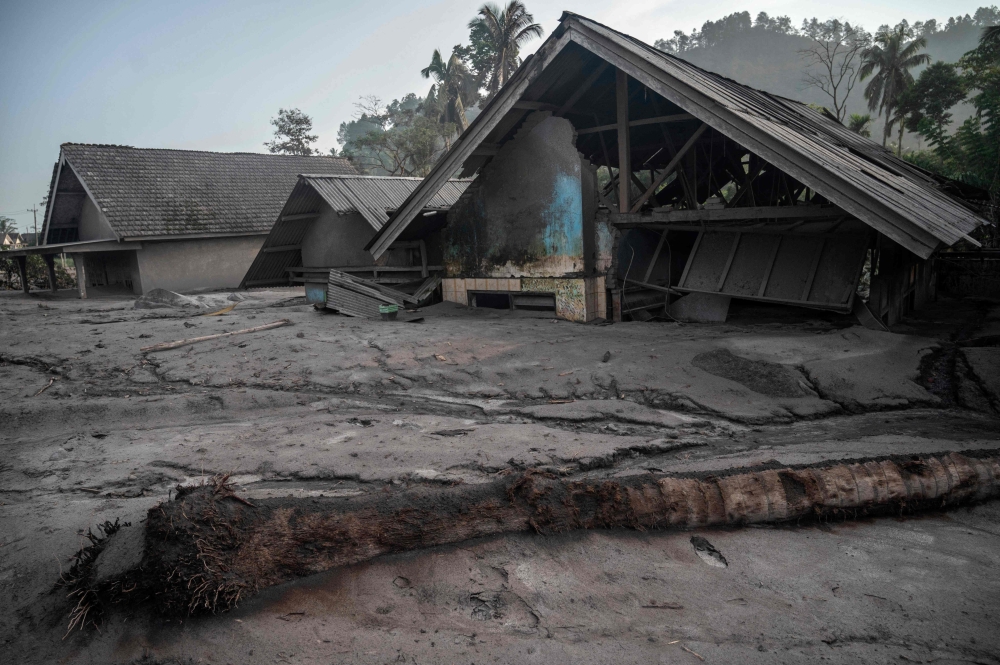 This picture shows damaged houses inundated by mud following a volcanic eruption by Mount Semeru at Kajar Kuning village in Lumajang on December 5, 2022. Photo by JUNI KRISWANTO / AFP