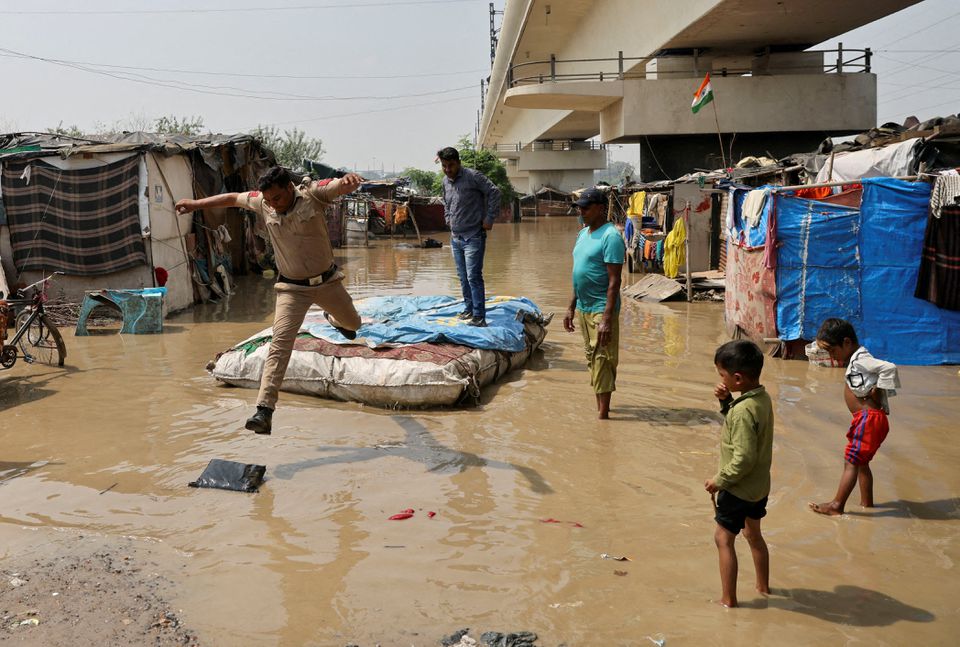 A policeman jumps off a makeshift raft after wading through a flooded area of a slum on the banks of the river Yamuna in New Delhi, India, September 28, 2022. REUTERS/Anushree Fadnavis/File Photo