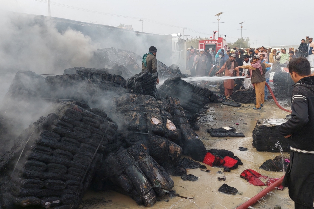 People douse a cargo supply truck after it was hit during the artillery shelling, in the Pakistan-Afghanistan border town of Chaman, Pakistan, on December 11, 2022. REUTERS/Abdul Khaliq Achakzai