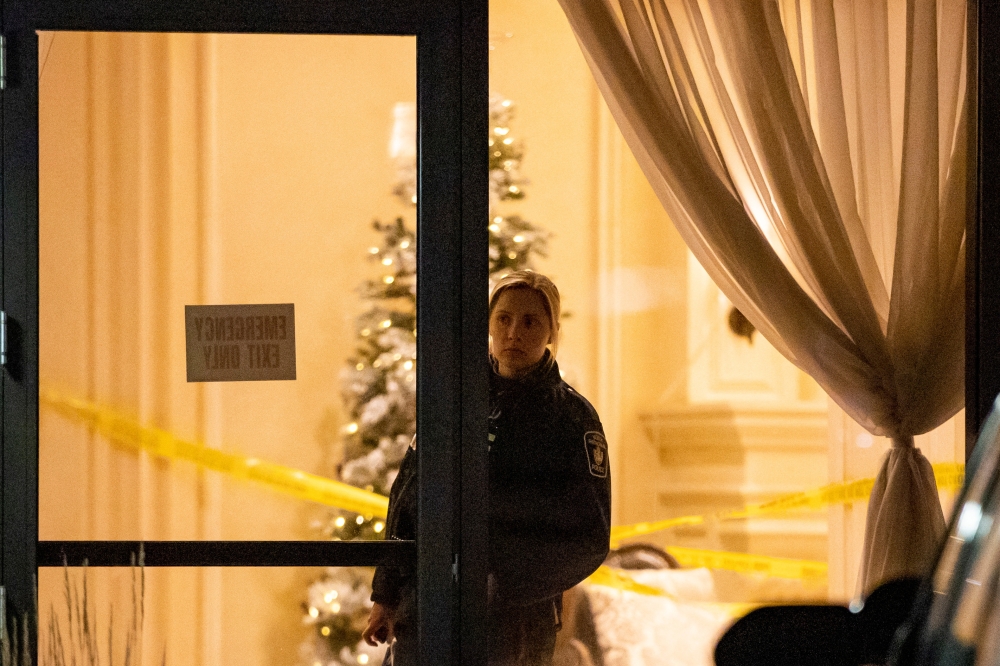 A police officer looks out from the lobby after a fatal mass shooting at a condominium building in the Toronto suburb of Vaughan, Ontario, Canada December 19, 2022. REUTERS/Carlos Osorio