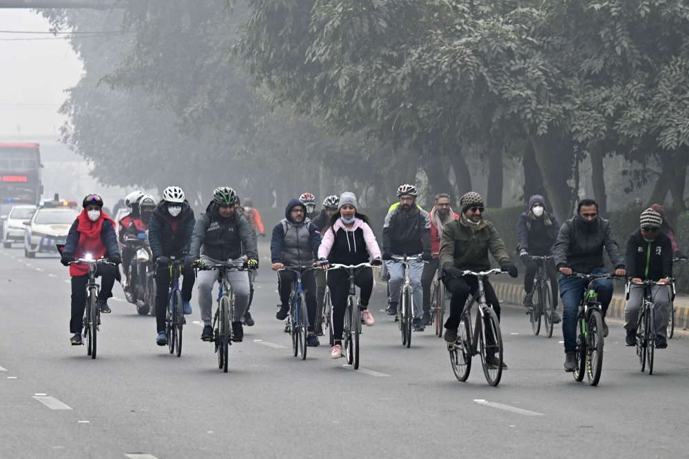 Cyclists take part in a pollution and smog awareness campaign as they ride along a street towards the Wagah border, in Lahore on December 25, 2022. (Photo by Arif ALI / AFP)