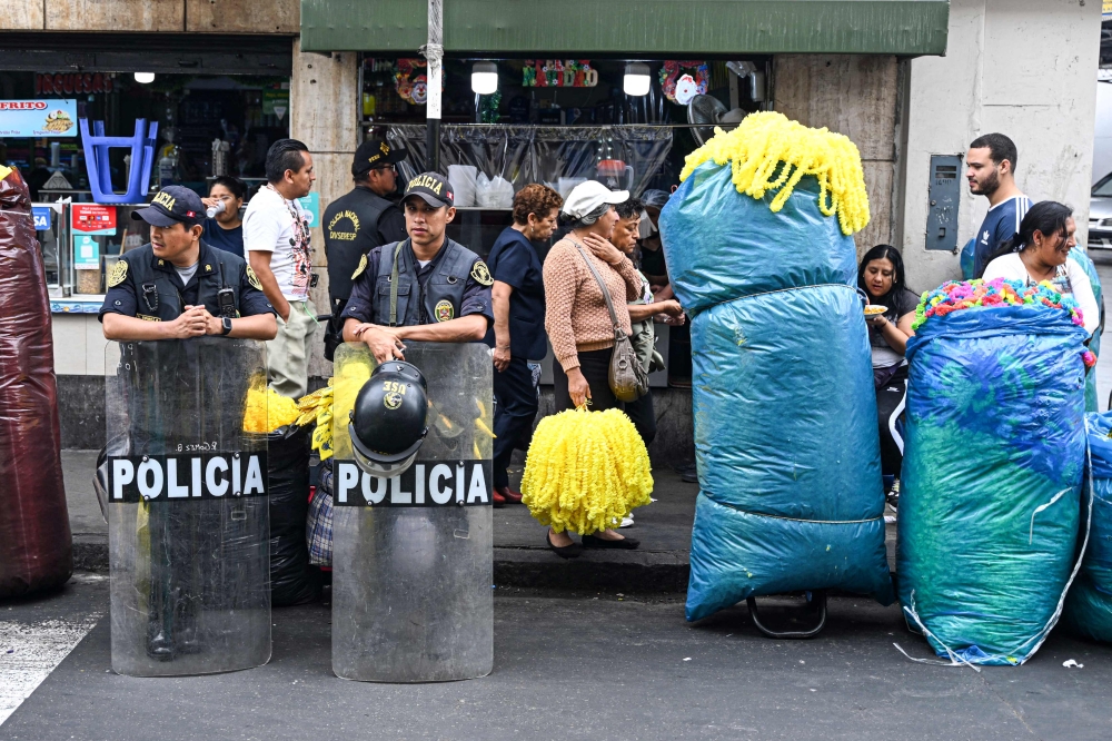 Police officers stand next to street vendors in downtown Lima on December 23, 2022. (Photo by Ernesto BENAVIDES / AFP)