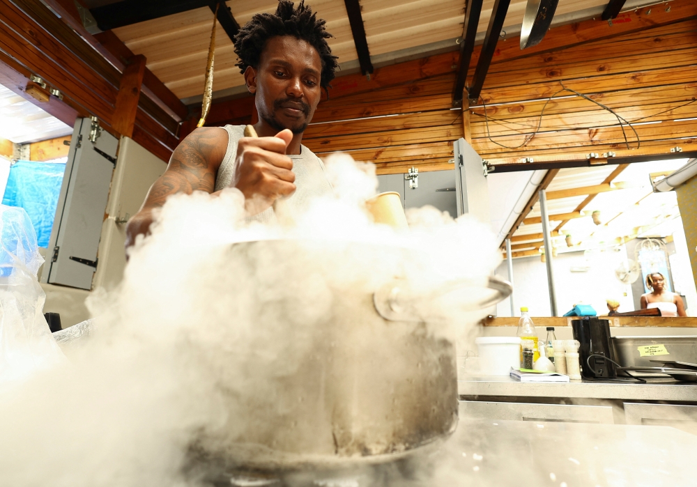 Tapi Tapi ice cream shop owner, Zimbabwean Tapiwa Guzha, mixes dry ice into the ice cream ingredients at his shop in Observatory, in Cape Town, South Africa, December 21, 2022. REUTERS/Esa Alexander