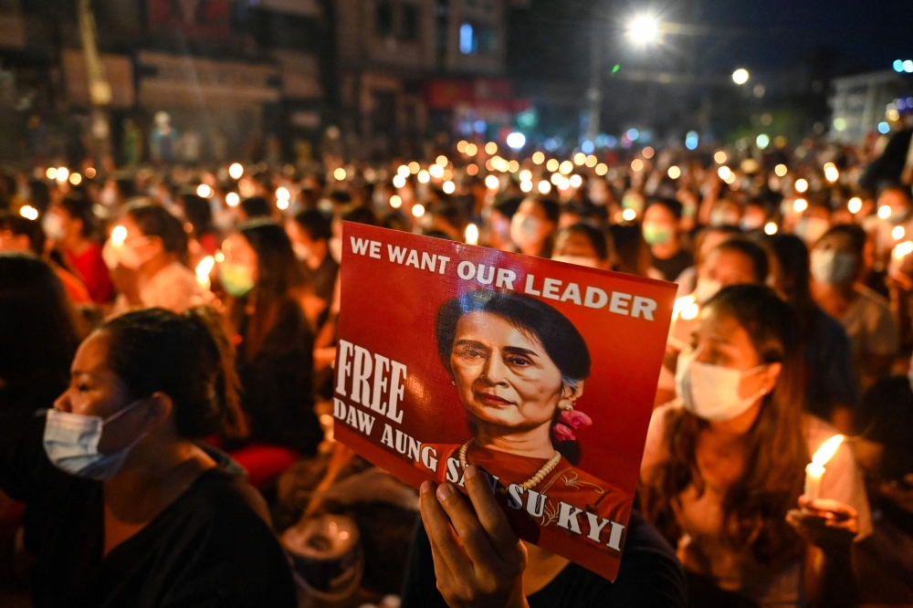 In this file photo taken on March 13, 2021, a protester holds a poster with an image of detained civilian leader Aung San Suu Kyi during a candlelight vigil to honour those who have died during demonstrations against the military coup in Yangon. (AFP)