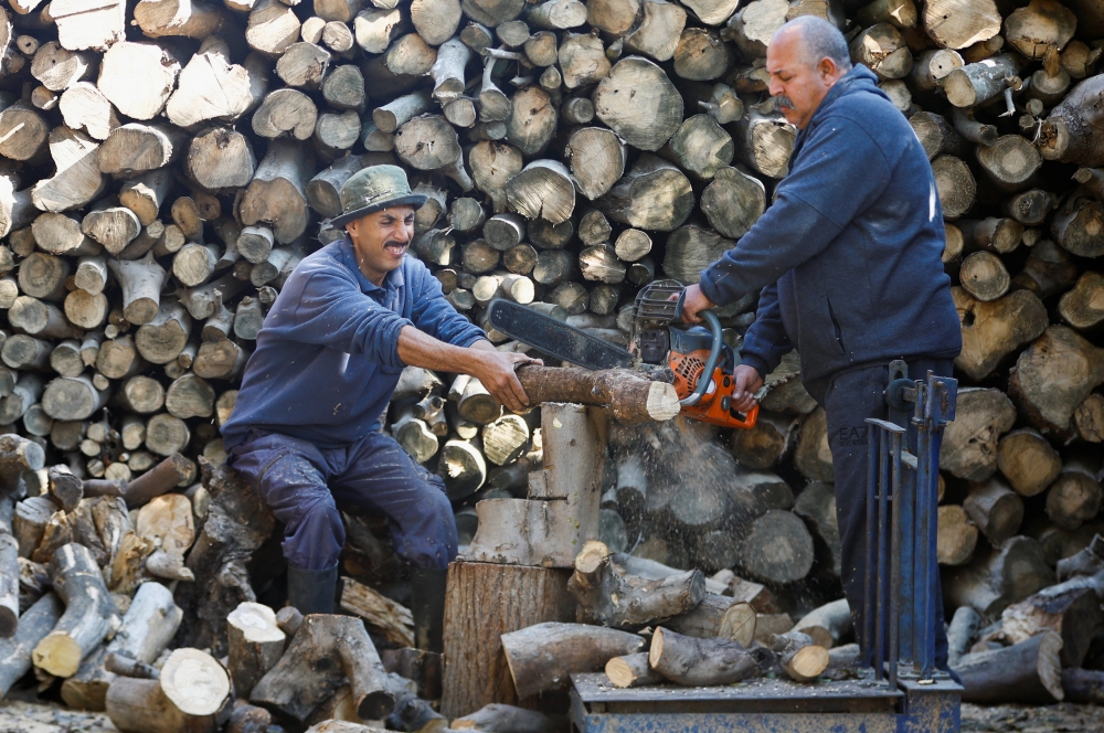 A Palestinian man Samir Hejji and his son cut wood for sale, in Gaza City, December 28, 2022. REUTERS/Ibraheem Abu Mustafa