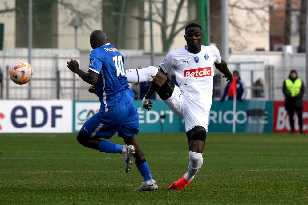 Marseille's Ivorian defender Eric Bailly (red) fouls Hyeres' midfielder Almike Moussa N'Diaye during the French Cup round of 64 football match between Olympique de Marseille (OM) and Hyeres at the Francis-Turcan Stadium in Martigues, southern France, on January 7, 2023. (Photo by Nicolas TUCAT / AFP)