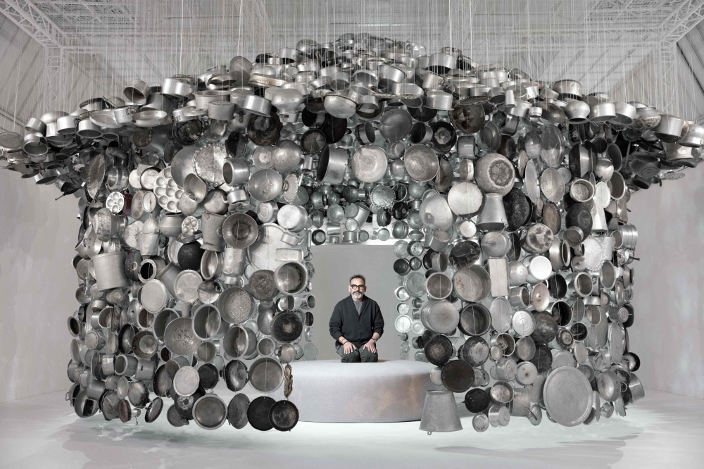 Indian artist Subodh Gupta poses in one of his installations, a hanging hut made with cooking pots collected from markets during his exhibition entitled 