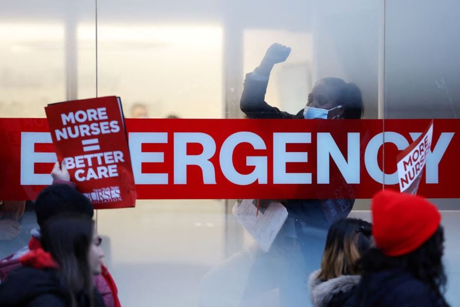 A hospital worker raises a fist as NYSNA nurses walk off the job, to go on strike at Mount Sinai Hospital in New York City, U.S. January 9, 2023. Reuters/Andrew Kelly
