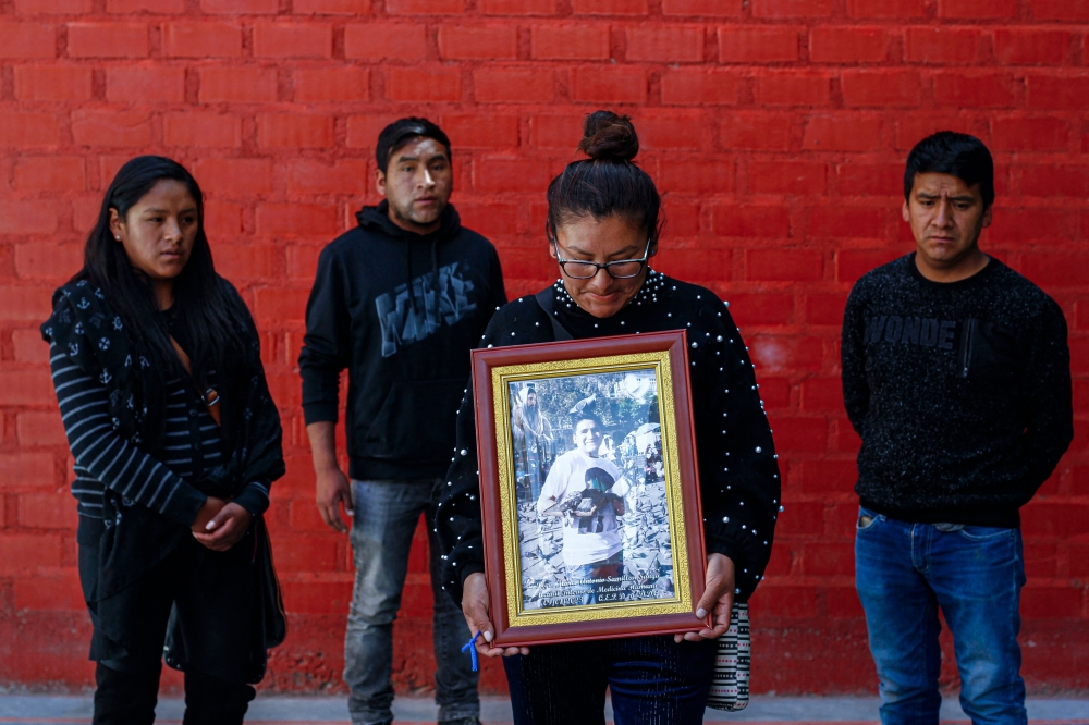(Left to right) Milagros Samillan, Edson Samillan, Ysabel Samillan and Juan Samillan, sisters and brothers of Marco Antonio Samillan Sanga, a biologist by profession and doctor in training who died during the protests in Juliaca, pose for a photo holding an image of Marco Antonio at his home in Juliaca in southern Peru on January 14, 2023. (Photo by Juan Carlos CISNEROS / AFP)