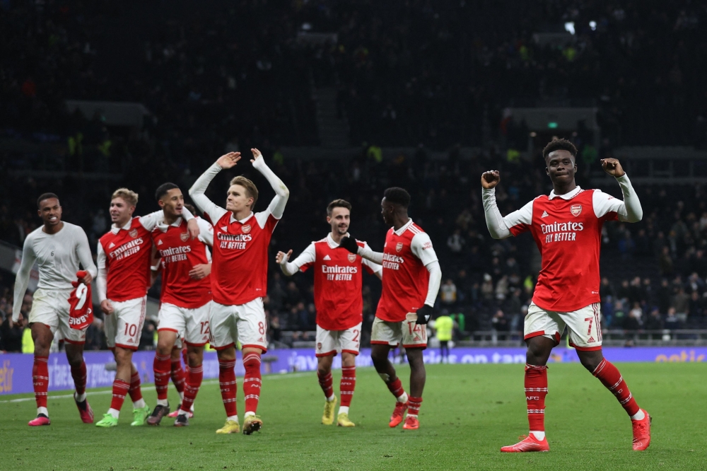 Arsenal's English midfielder Bukayo Saka (R) celebrates with teammates on the pitch after the English Premier League match between Tottenham Hotspur and Arsenal at Tottenham Hotspur Stadium in London, on January 15, 2023.  (Photo by ADRIAN DENNIS / AFP)
