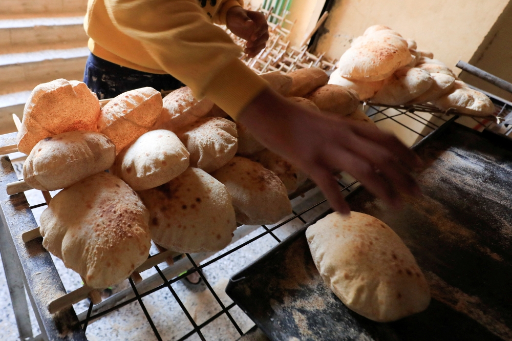 An Egyptian worker removes loaves of bread from the oven at a bakery in Cairo's southeastern Mokattam district, as the prices of basic goods in Egypt have risen since Russia’s invasion of Ukraine, in Egypt, March 16, 2022. (REUTERS/Amr Abdallah Dalsh)