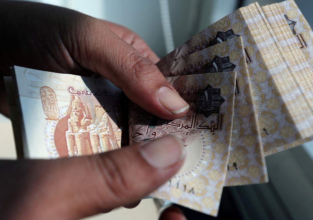 A man counts Egyptian pounds outside a bank in Cairo, Egypt on October 24, 2016. File Photo / Reuters
